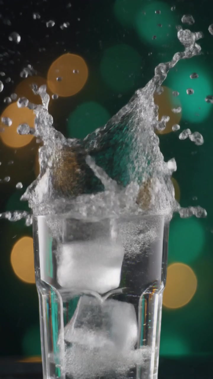 Water Pouring into Glass with Ice Cubes and Bokeh Background