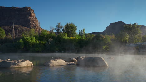 scenic nature scene of a misty river with rock boulders. wide shot