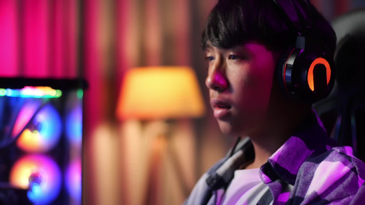 컴퓨터에서 비디오 게임을 하는 심각한 아시아 십대 소년 게이머의 클로즈업