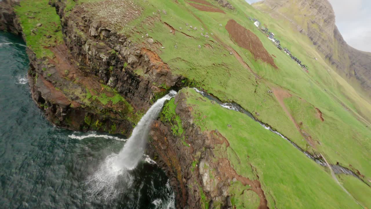 A fast FPV flight over a dramatic Faroe waterfall surrounded by lush green cliffs
