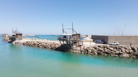 Wide-angle-orbiting-drone-shot-of-an-old-wooden-structure-called-a-"Trabucco"-that-is-an-ancient-method-of-fishing-using-this-platform-with-a-large-net-for-fishing