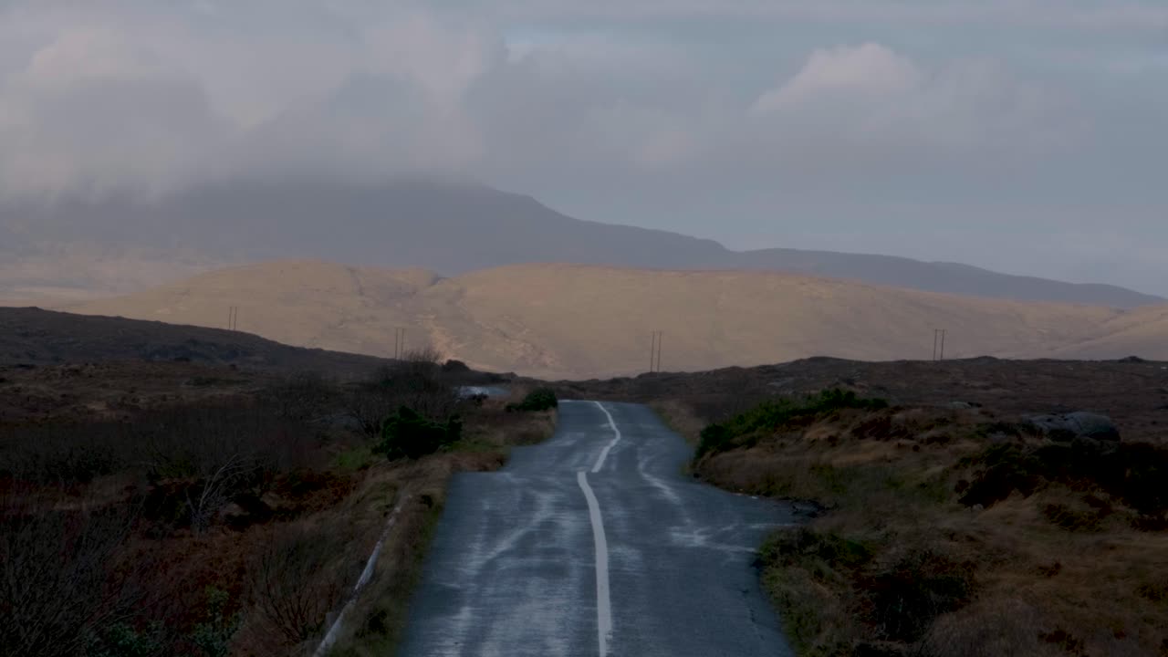 Straight country road stretching through the wild Irish landscape under a cloudy sky