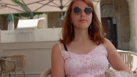 girl in sunglasses eating a cannoli pastry at caffe cordina in valletta, malta