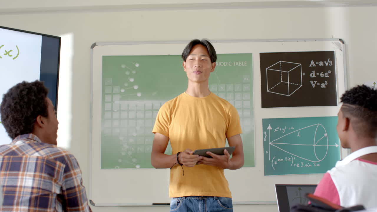 In high school, asian male student holding tablet and presenting students in classroom