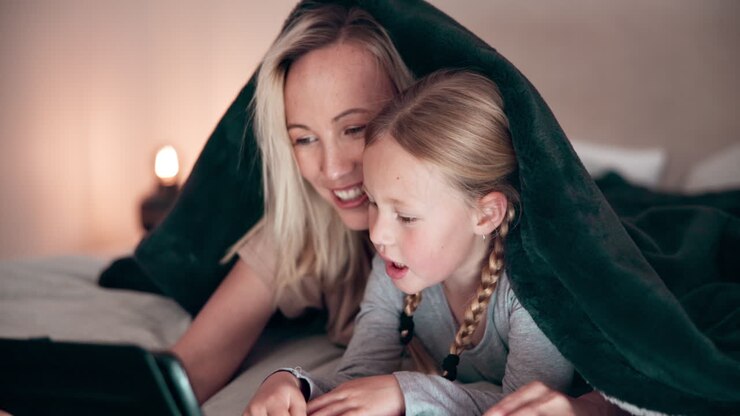 Mama, Tochter und Tablet nachts im Schlafzimmer