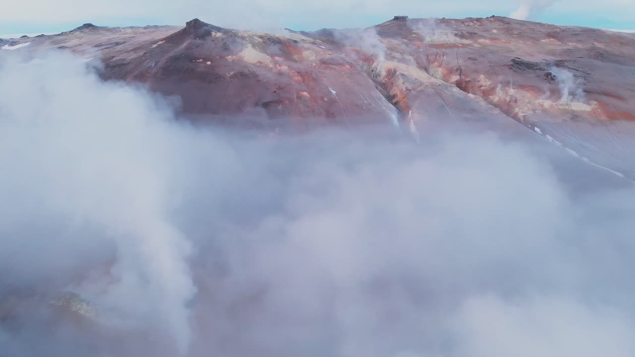 Smoke clouds around hills in volcanic geothermal landscape in Iceland.