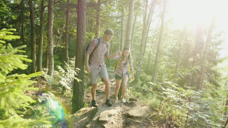 a young couple travels along a picturesque place in the forest a man helps a woman to walk along the