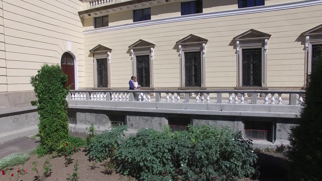 Wedding Day. Wedding Session. Aerial shot of a passionate kiss of wedding couple standing on old stone balcony