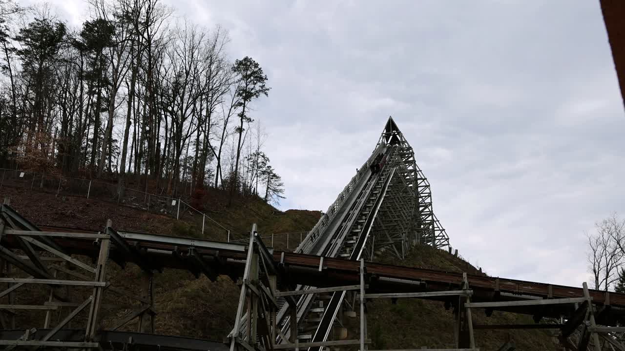 Riders experience the thrill of acceleration while being launched on roller coaster up steep hill. Amusement park ride with banks, turns, incline and drops. Coaster cars speed away from the station.