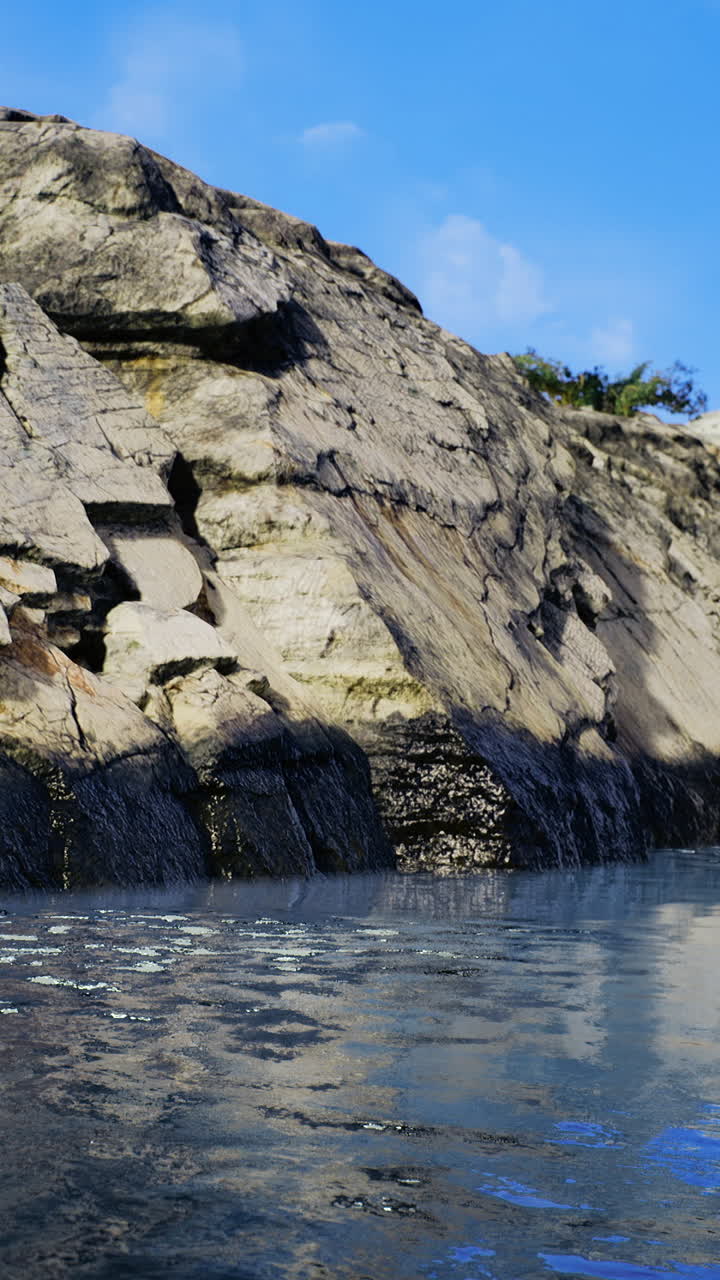 Rocky coastline meets calm water under a clear blue sky at midday