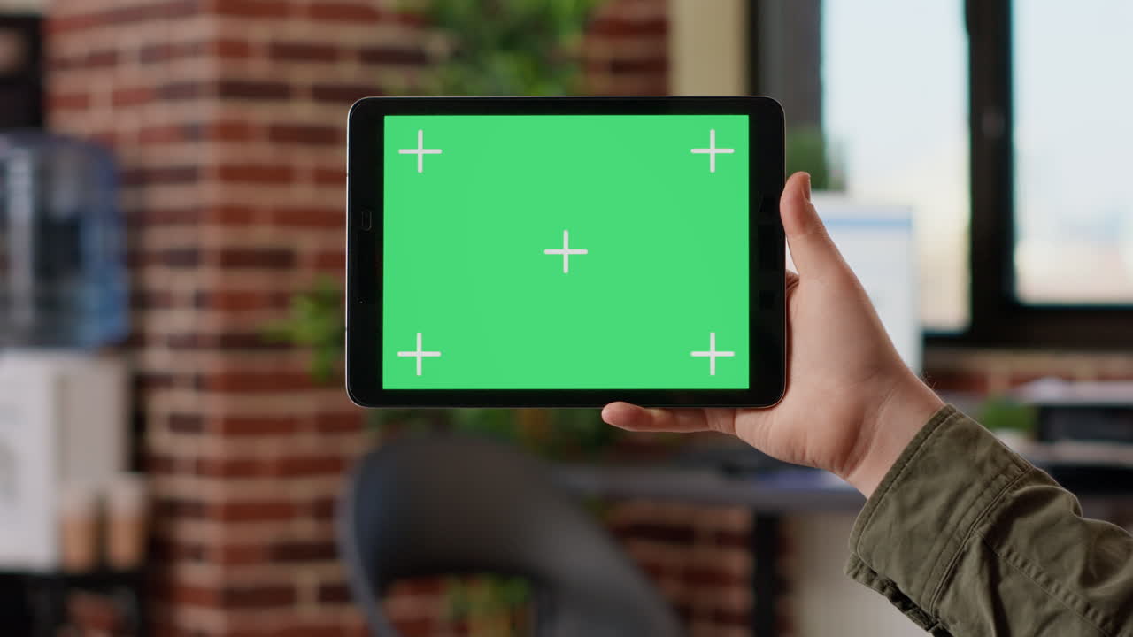 Male freelancer holding horizontal greenscreen on digital gadget