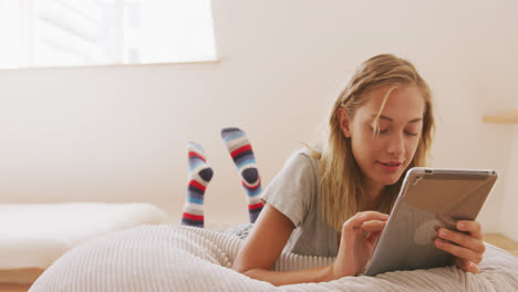 woman using digital tablet while laying on a bean bag indoors