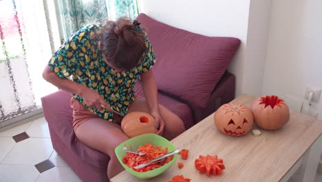 scene with young woman carving pumpkin for halloween