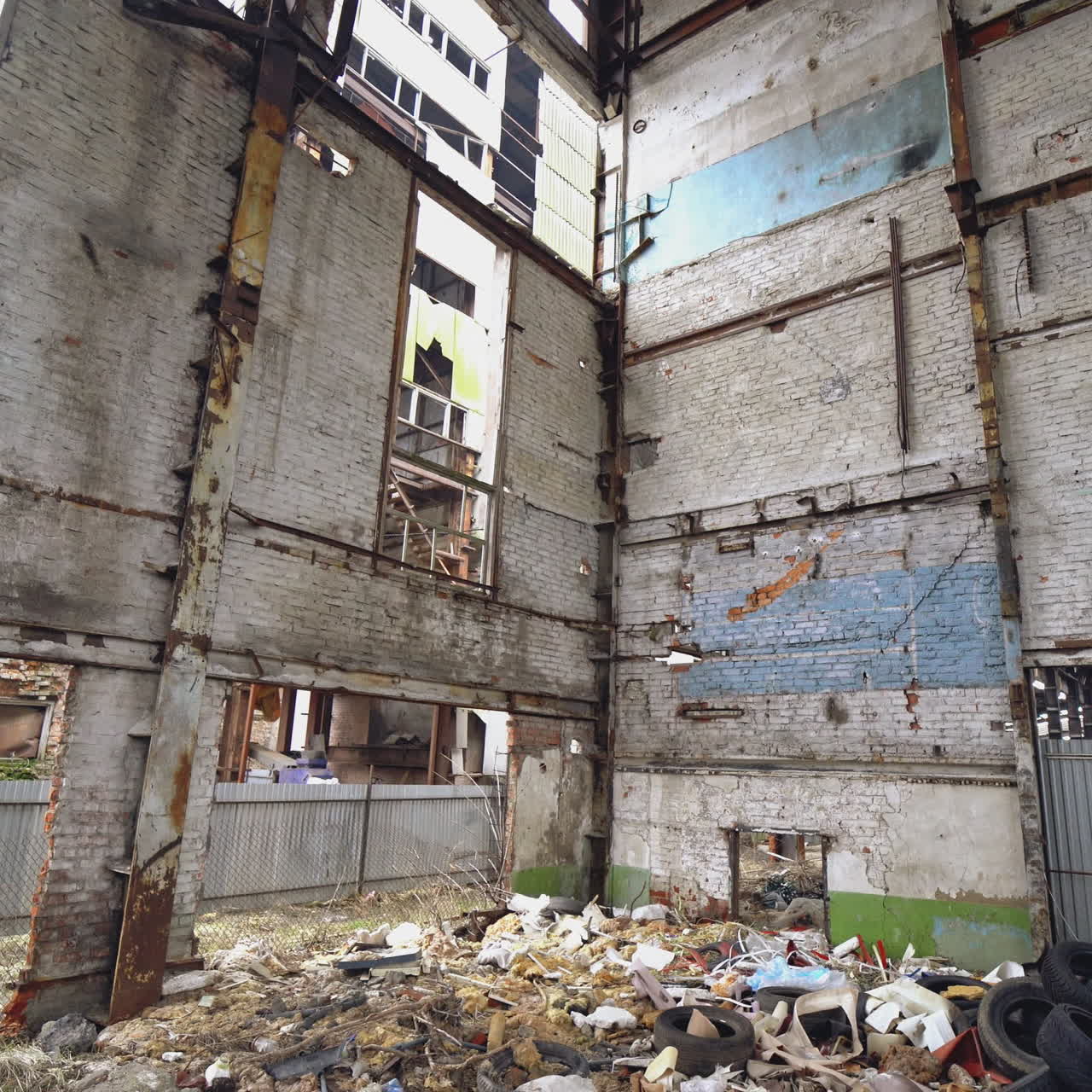 Big bunch of old tires on the background of a ruined plant. Pile of used tires lays on a dirty floor.