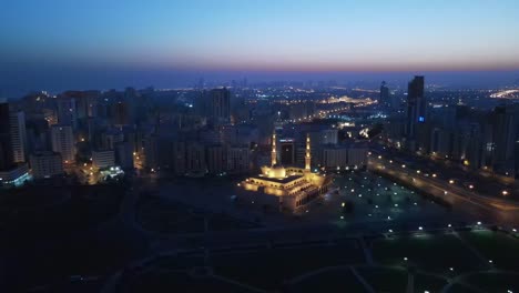 sharjah: early morning aerial view of sharjah city, king faisal mosque illuminated during sunrise in united arab emirate