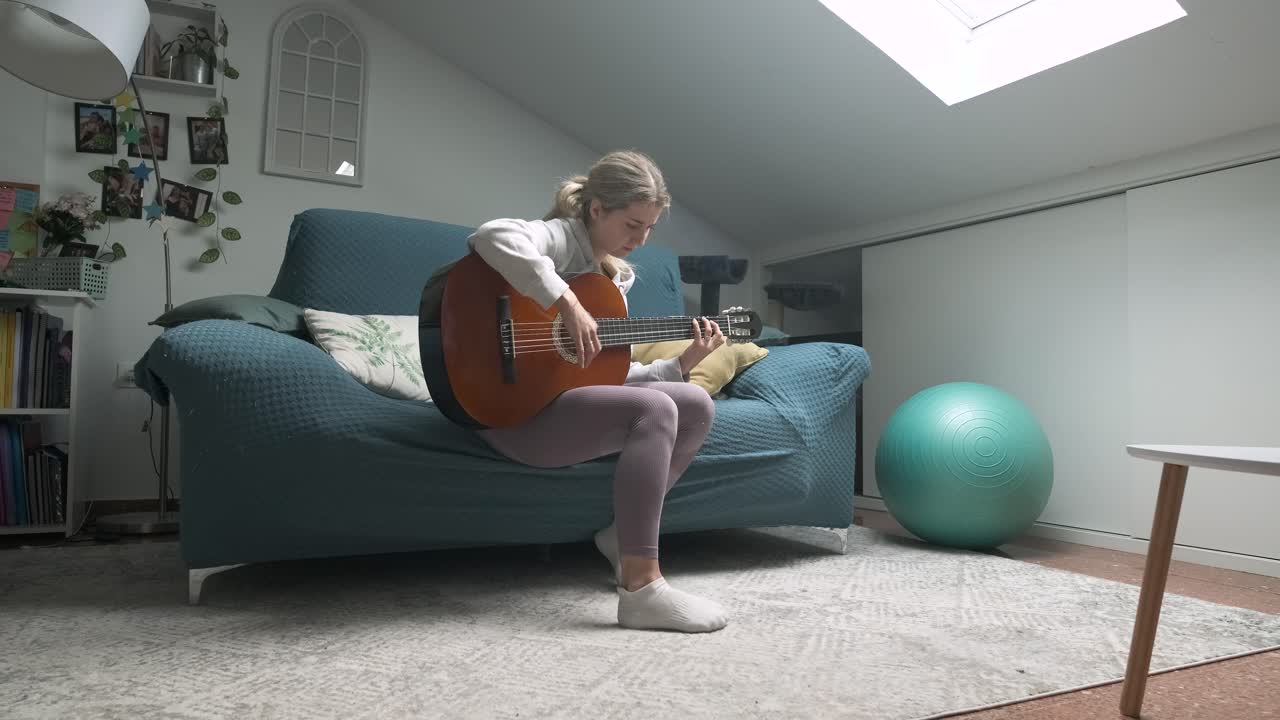 Young woman enjoying a relaxed moment while playing acoustic guitar in her cozy living room
