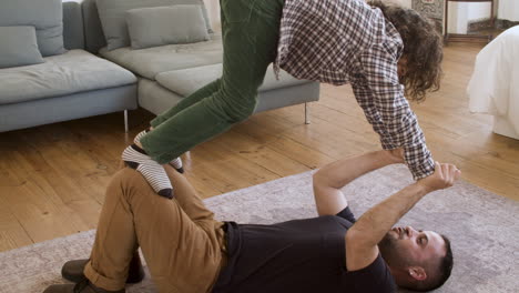 un padre feliz jugando con su hijo en el suelo de su casa.