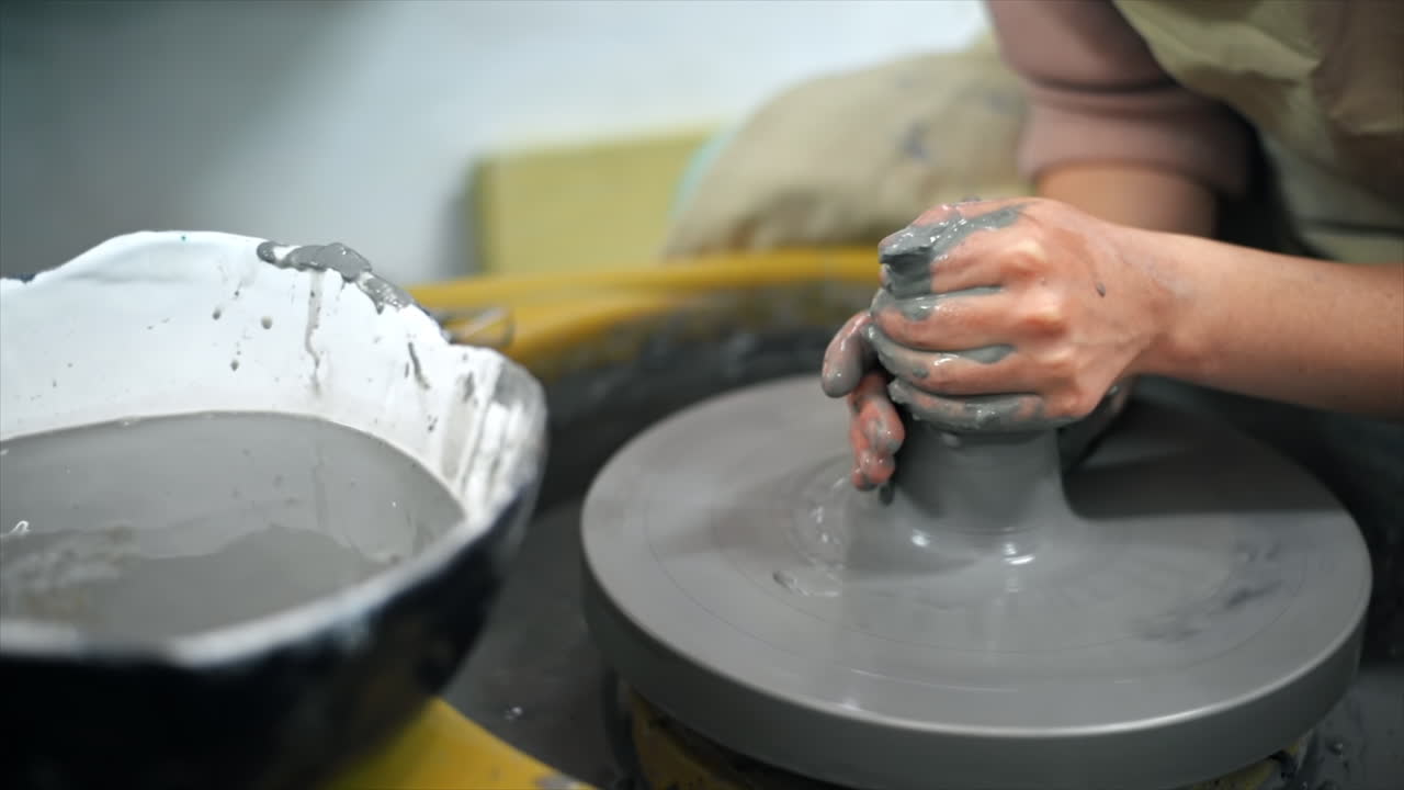 The master of sculpting pottery working in a studio. Shaping the clay on the potter's wheel. Slow motion