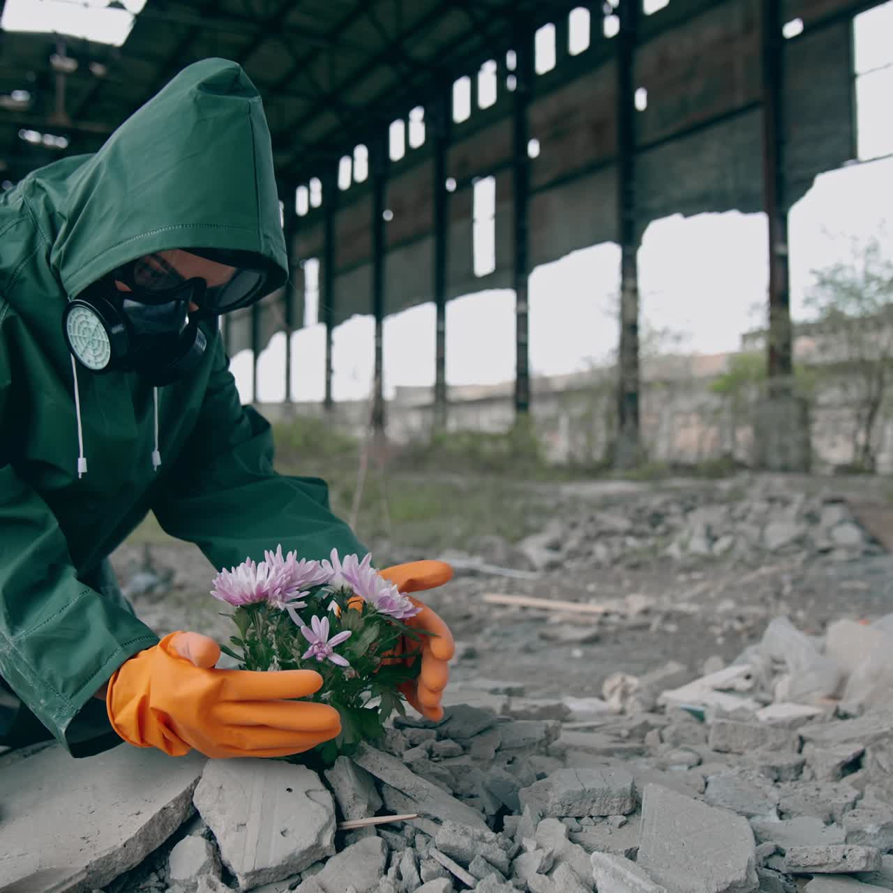 Dando uma nova vida ao nosso planeta. Ecologista vestindo um traje de segurança e máscara de gás, preparando-se para colocar flores em um local abandonado ao redor do lixo do prédio. Conceito de ataque bioquímico
