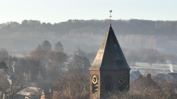 Panning flight along the tower of the church in Westouter in the Flemish province of West Flanders in Belgium