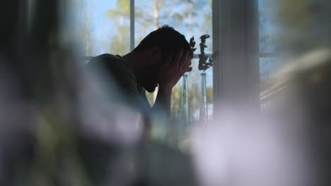 silueta de hombre solitario llorando en su casa, vista lateral