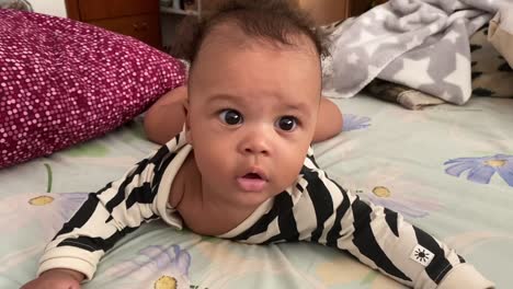5 month lovely afroeuropean baby with big black eyes wearing a black and white body