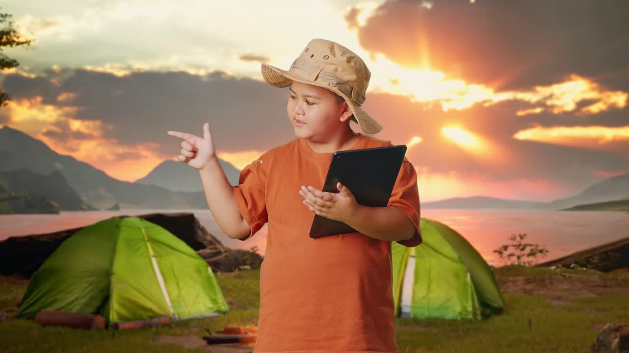 Boy with tablet at a campsite at sunset