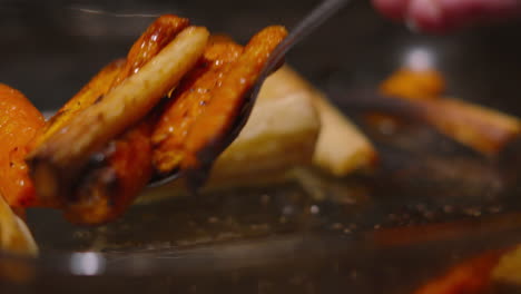 spoon coating freshly oven roasted british carrots and parsnips in olive oil in slow motion getting ready to serve 4k