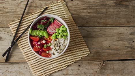 Composition-of-bowl-of-rice-and-vegetables-with-chopsticks-on-wooden-background