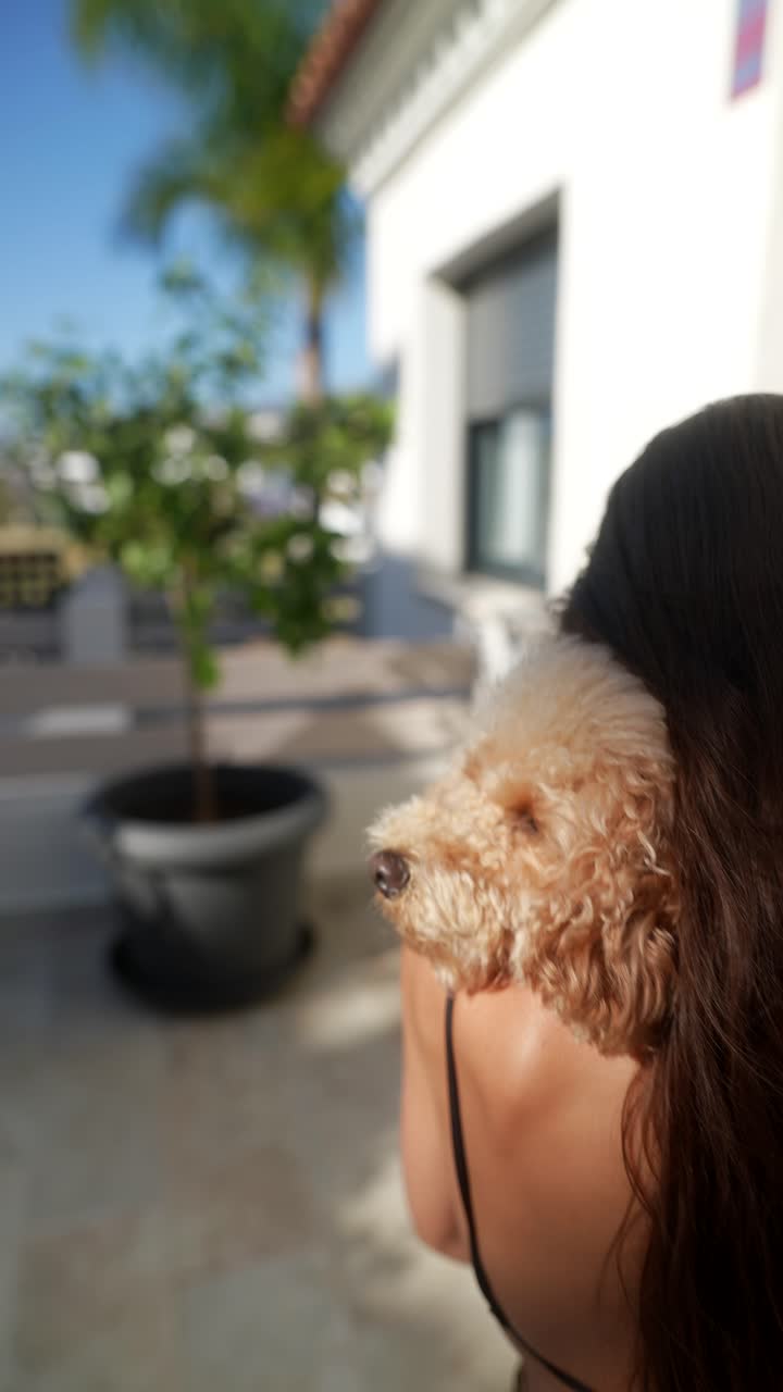 mujer sosteniendo un caniche en un patio