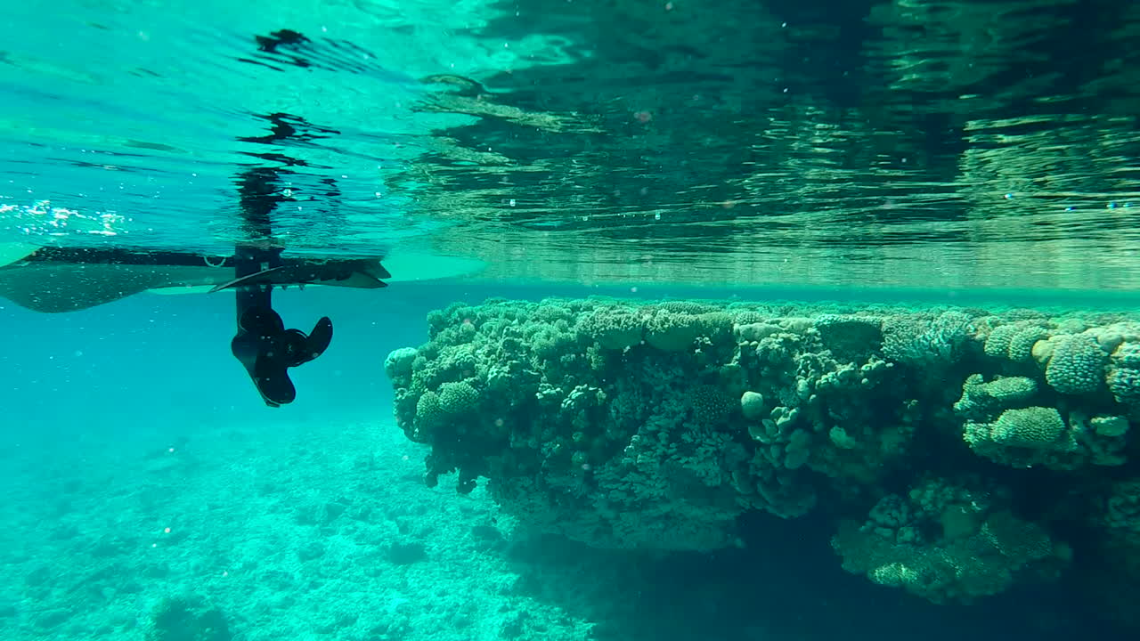 hélice de casco de barco submarino flotando pasado arrecife de coral slomo de mano