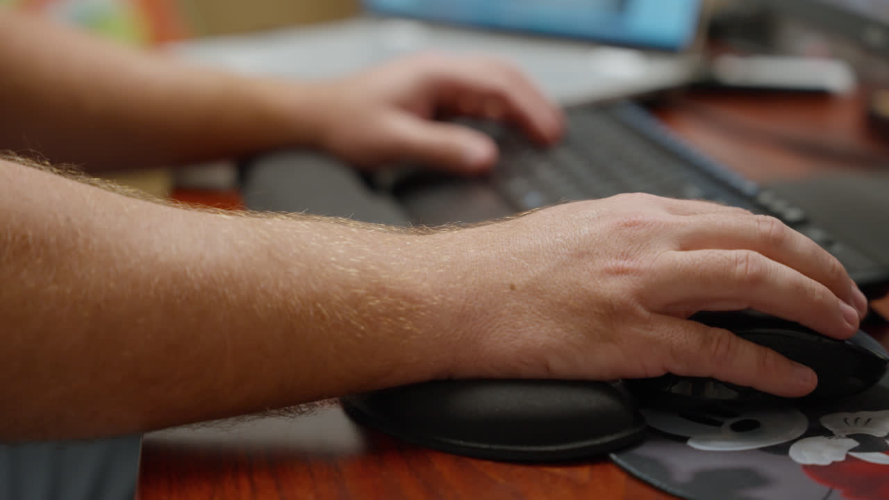 Hands typing on keyboard and using mouse simultaneously at workstation