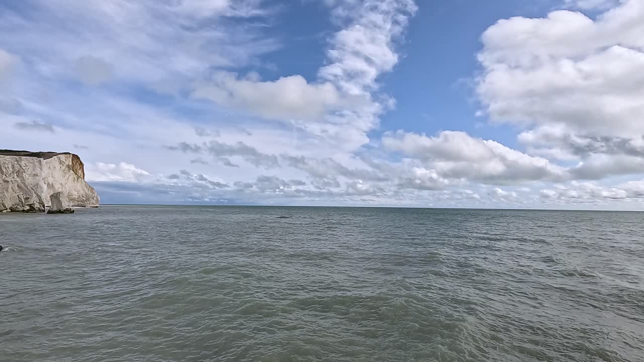 olas golpeando acantilados bajo un cielo nublado