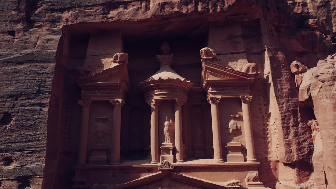 luz del sol iluminando escultura tallada en roca detalles de la tumba del tesoro fachada tallada en piedra, petra, paralaje aéreo