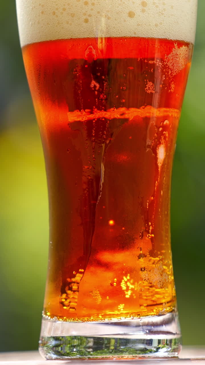 Fresh beer with bubbles in glass. Cold brewed drink in a glass with water drops over blur background. Craft beer close up. Vertical video