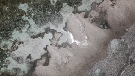 above view of seashore meets low tide river in antigua islands. aerial ascending shot