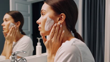 woman applying face cream or mask in the bathroom