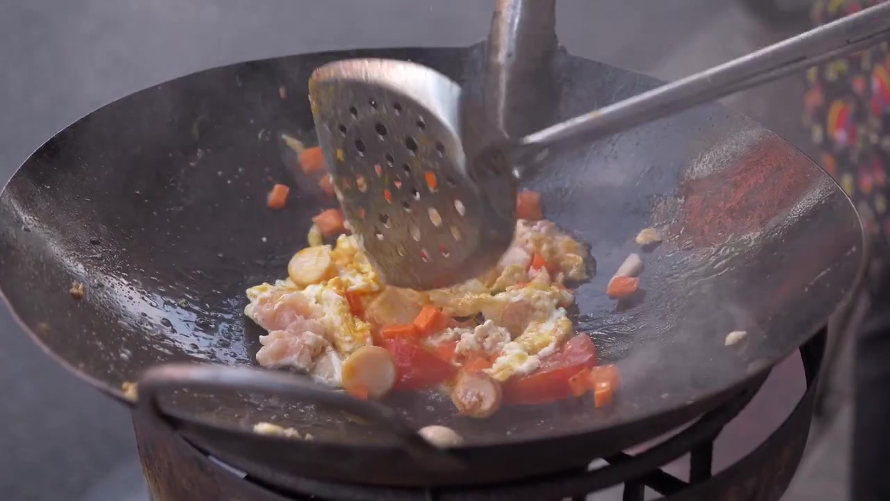 Venditore ambulante che cucina un piatto tailandese a base di uova in un wok tradizionale lungo Charoen Krung Road a Bangkok, Thailandia
