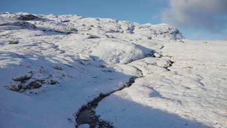 un arroyo poco profundo en la tundra cubierta de nieve