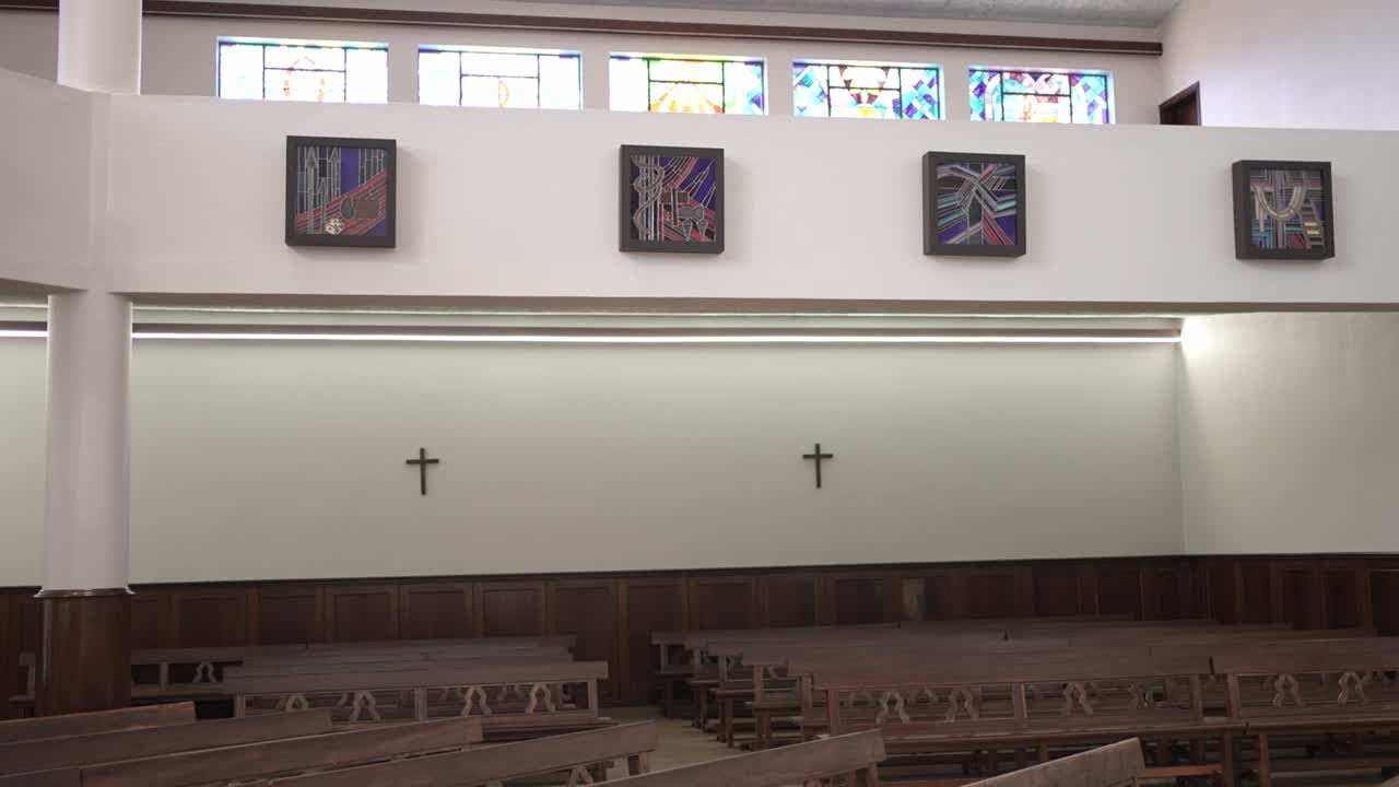 화려한 스테인드글라스 아래 나무 벤치로 가득 찬 밝고 현대적인 교회