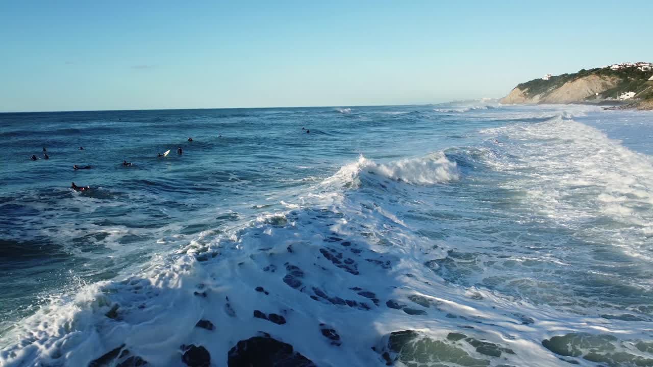 Ocean waves with surfers near a coastline