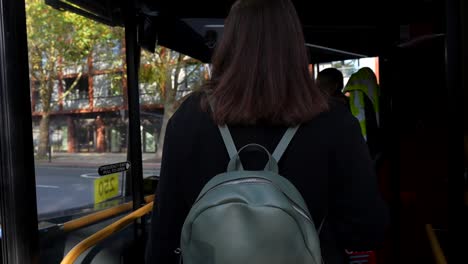 woman waits to board london bus as another passenger exits due to insufficient card balance
