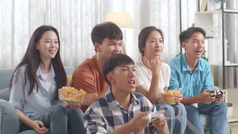 asian teenagers playing video games at home. one win and one lost