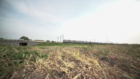 two highspeed trains pass each other near a bridge along a long rural stretch, nmbs, belgium