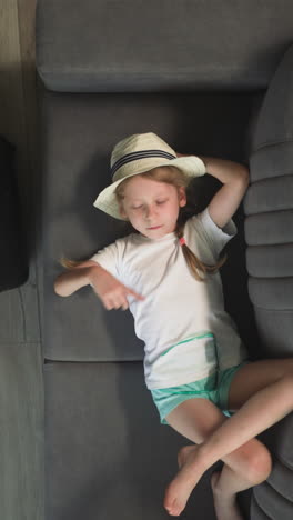 tired girl waves hand imitating conducting orchestra on sofa while toddler playing with airplane. children take break after long flight upper view