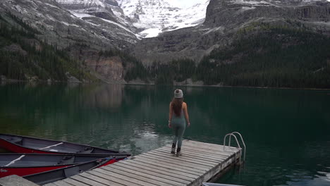 lonely woman walking at wooden dock on lake o'hara, yoho national park, canada