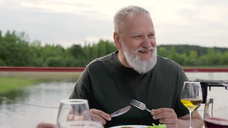 a group of senior friends talk and laugh while they have dinner