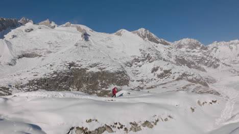 toma aérea en suiza con una persona caminando con raquetas de nieve en un día soleado con un glaciar detrás