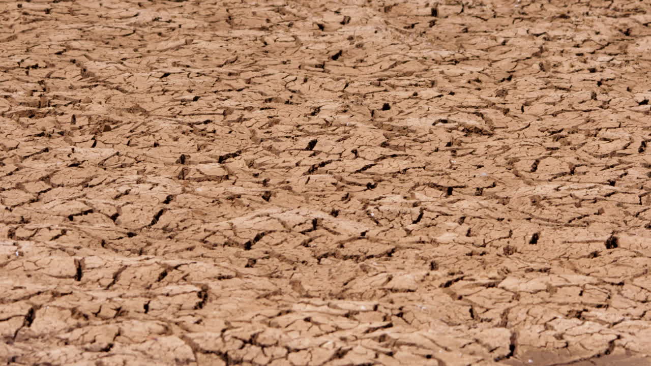 Wide pan shot of cracked ground during a hot afternoon in Kenya