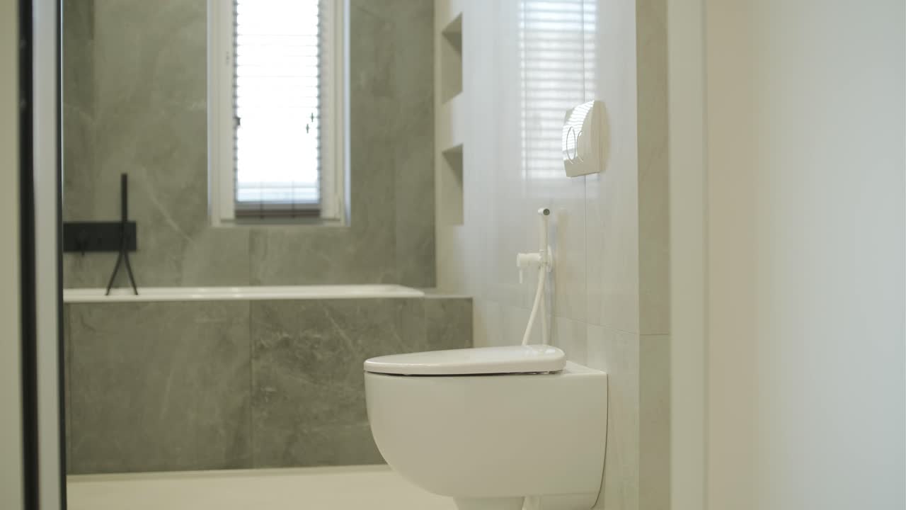 baño moderno con inodoro montado en la pared y diseño de azulejos grises